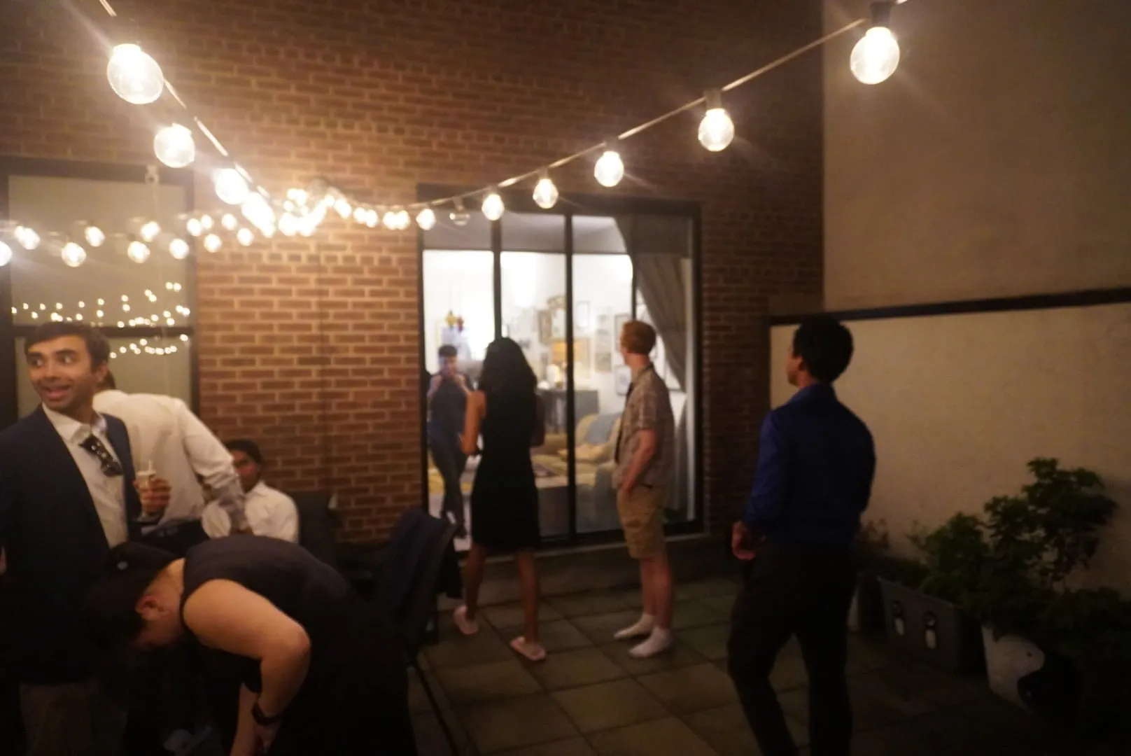 guests mingling on a rooftop under string lights at night