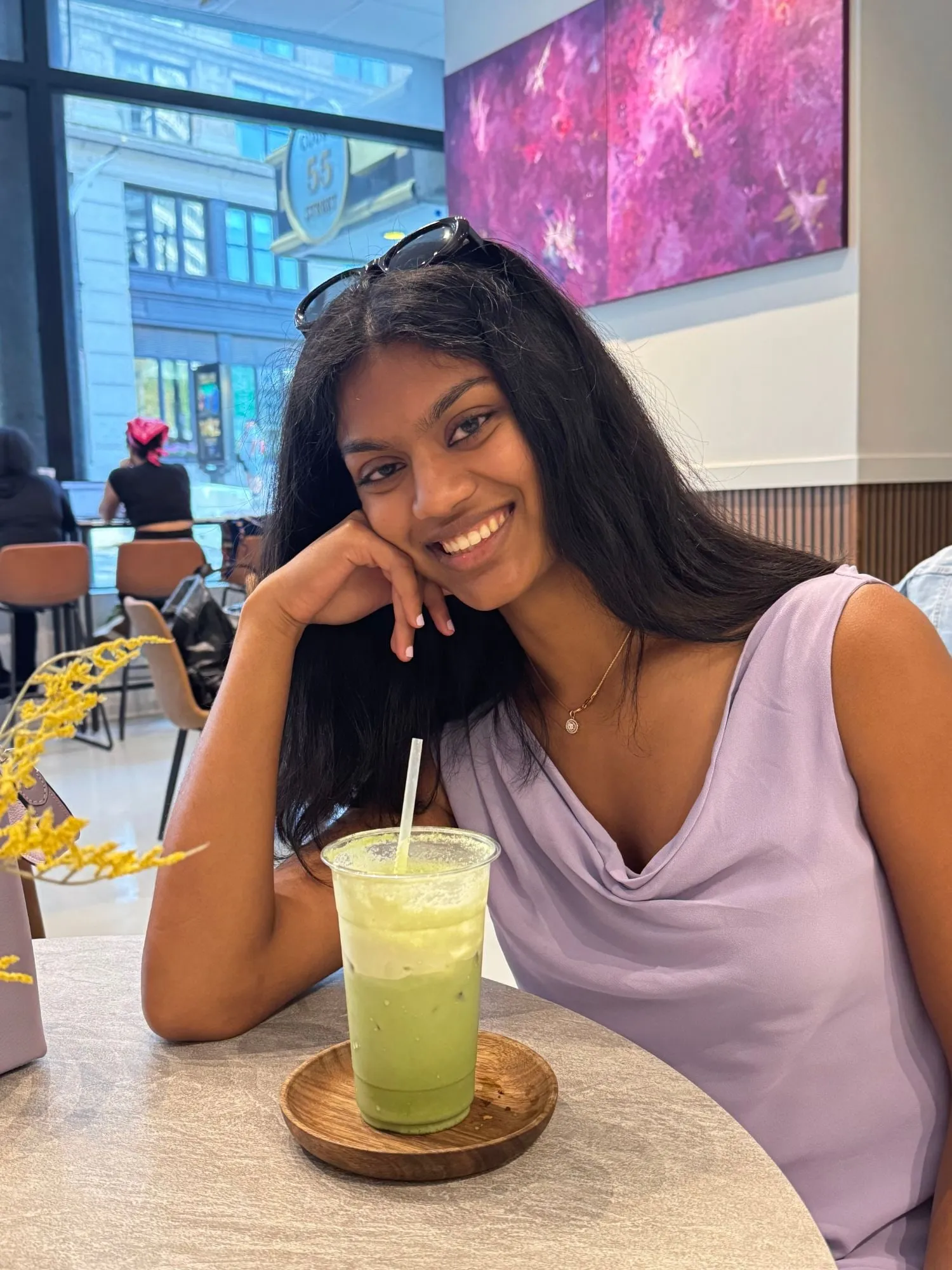 sahithi muthyala, smiling at a café table with an iced matcha